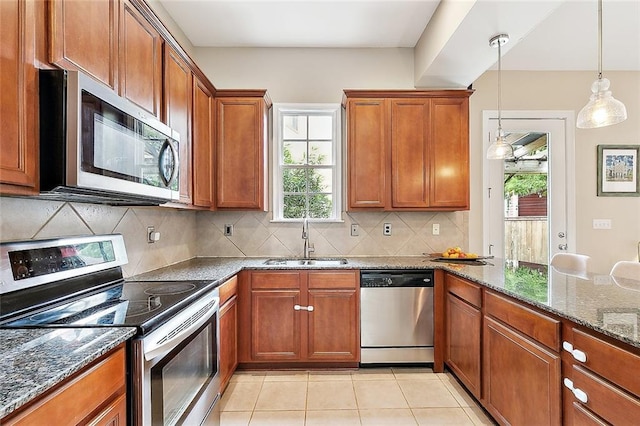 kitchen featuring a healthy amount of sunlight, brown cabinetry, appliances with stainless steel finishes, and a sink