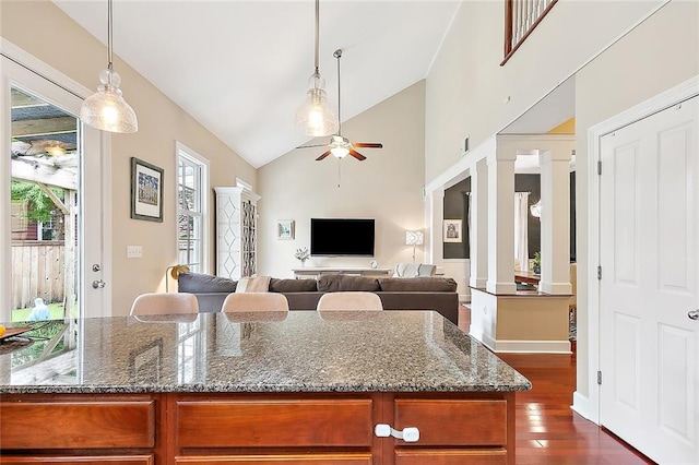 kitchen featuring dark stone counters, ornate columns, high vaulted ceiling, dark wood-type flooring, and ceiling fan