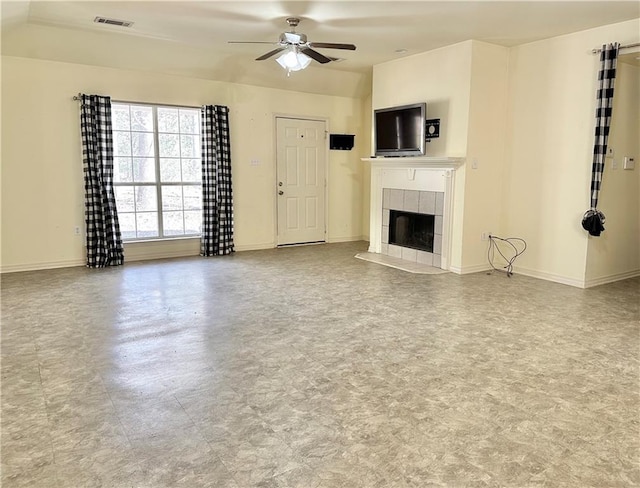 unfurnished living room featuring a tiled fireplace and ceiling fan