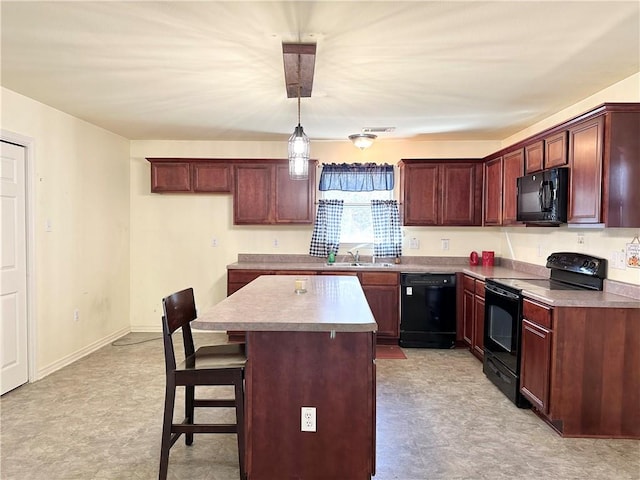 kitchen featuring a kitchen island, a breakfast bar area, black appliances, decorative light fixtures, and sink