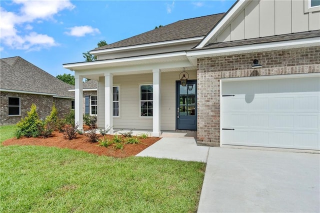 view of exterior entry featuring a garage, a yard, and a porch