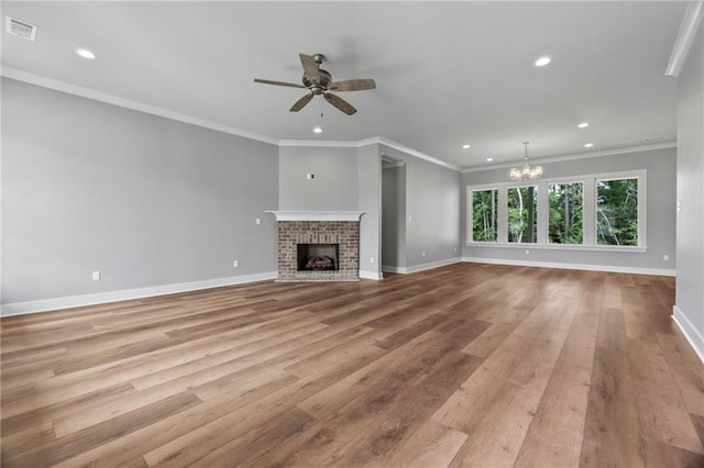 unfurnished living room with a brick fireplace, ceiling fan with notable chandelier, light hardwood / wood-style flooring, and ornamental molding