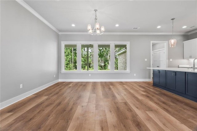 interior space with an inviting chandelier, sink, crown molding, and light wood-type flooring