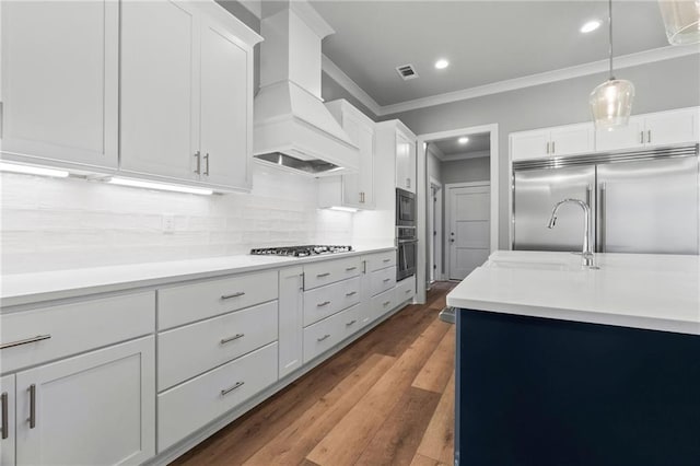 kitchen with pendant lighting, sink, premium range hood, white cabinetry, and black appliances