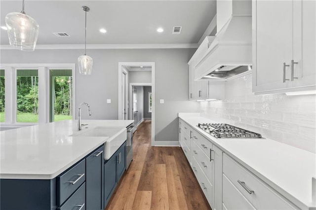 kitchen featuring pendant lighting, white cabinets, custom range hood, and stainless steel gas stovetop