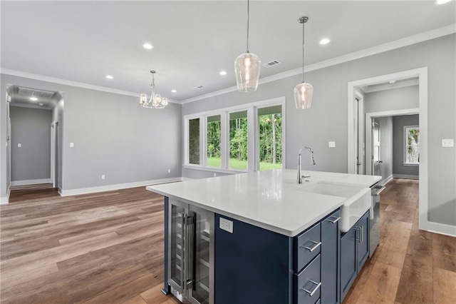 kitchen with sink, blue cabinetry, hanging light fixtures, a healthy amount of sunlight, and a center island with sink