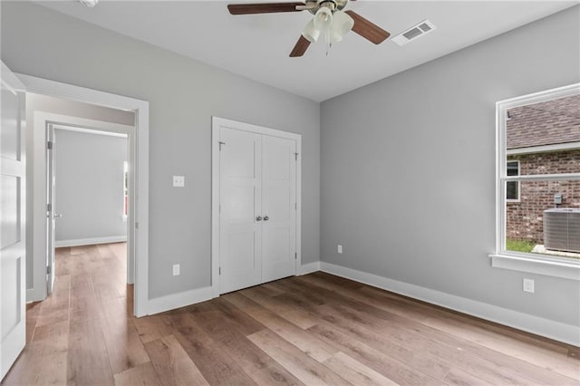 unfurnished bedroom featuring visible vents, ceiling fan, a closet, baseboards, and wood finished floors