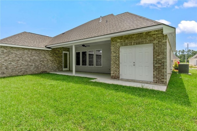 rear view of house featuring roof with shingles, a yard, a patio area, and central AC unit