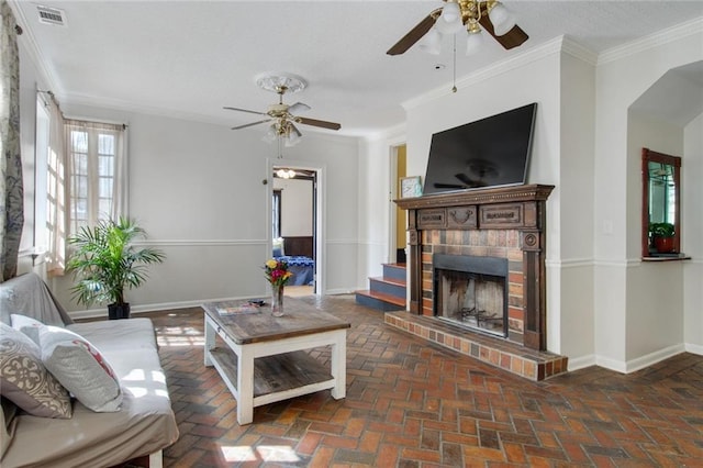 living room featuring ceiling fan, ornamental molding, and a brick fireplace