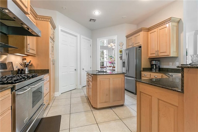 kitchen featuring appliances with stainless steel finishes, a center island, light tile patterned flooring, light brown cabinetry, and dark stone counters