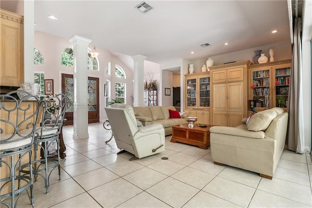 living room featuring decorative columns and light tile patterned floors