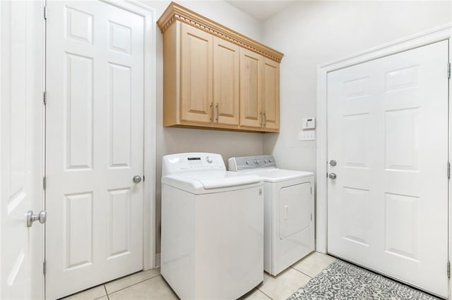 laundry area with light tile patterned flooring, washing machine and clothes dryer, and cabinets