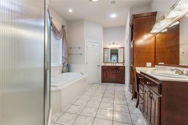 bathroom featuring tile patterned flooring, vanity, and tiled tub