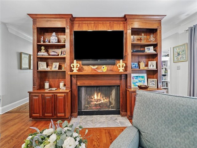 living room featuring crown molding, a tiled fireplace, and light hardwood / wood-style flooring