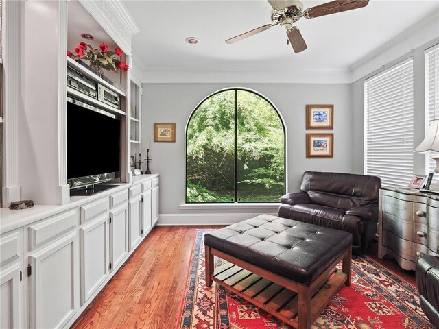 living area featuring ceiling fan, ornamental molding, light hardwood / wood-style flooring, and a healthy amount of sunlight