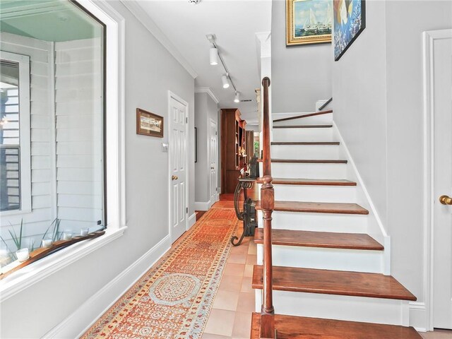 stairway featuring light tile patterned flooring, track lighting, and ornamental molding