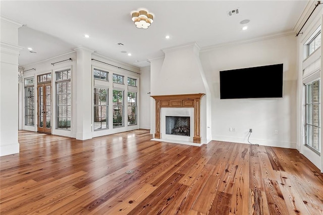 unfurnished living room featuring ornate columns, ornamental molding, a high end fireplace, and light hardwood / wood-style floors