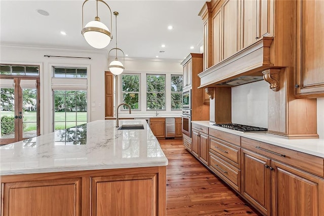 kitchen featuring a kitchen island with sink, sink, pendant lighting, and stainless steel appliances