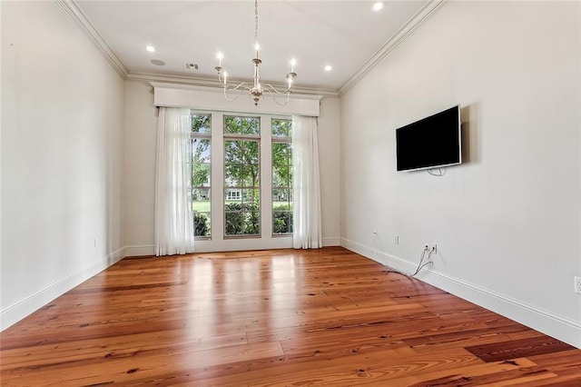 spare room with ornamental molding, hardwood / wood-style floors, and a chandelier