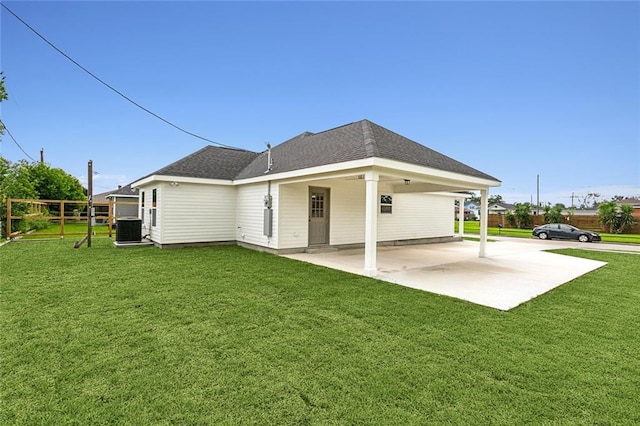 rear view of property with fence, a lawn, cooling unit, and roof with shingles