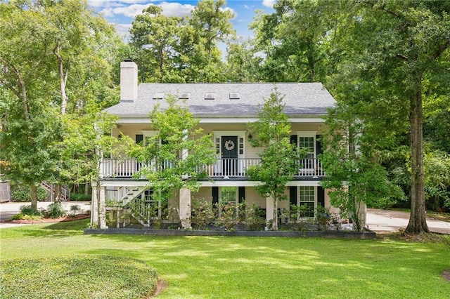 view of front of property with a balcony and a front lawn