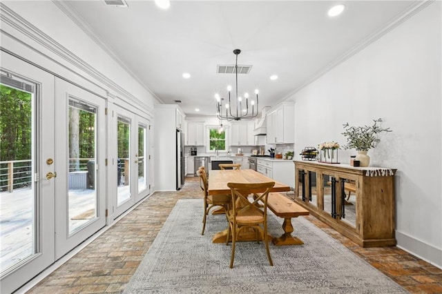 dining area with sink, crown molding, french doors, and a notable chandelier