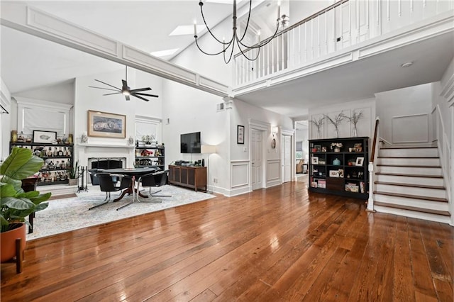 living room with ceiling fan with notable chandelier, wood-type flooring, and a towering ceiling