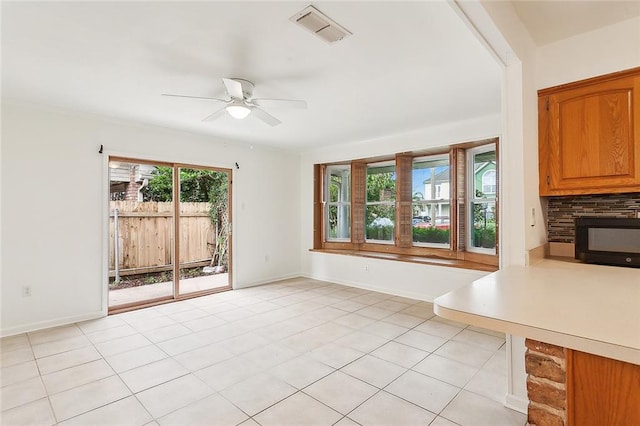 interior space featuring light tile patterned flooring, a stone fireplace, and ceiling fan