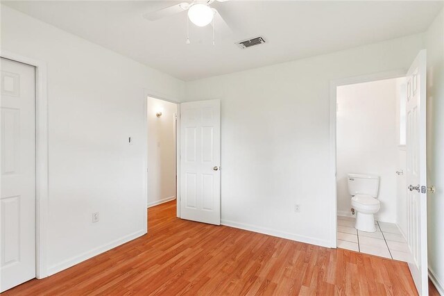 unfurnished bedroom with ceiling fan, ensuite bathroom, and light hardwood / wood-style flooring