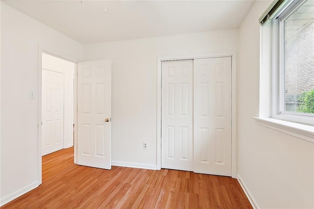 unfurnished bedroom with light hardwood / wood-style flooring and a closet