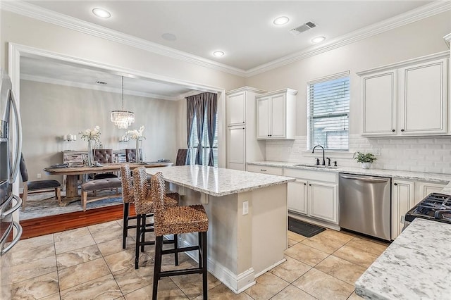 kitchen featuring white cabinets, sink, a kitchen island, decorative light fixtures, and stainless steel appliances