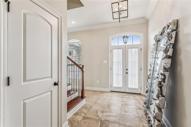 foyer entrance with ornamental molding, french doors, and a notable chandelier