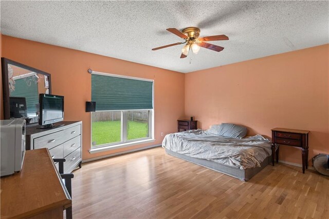 bedroom featuring light hardwood / wood-style floors, a textured ceiling, and ceiling fan