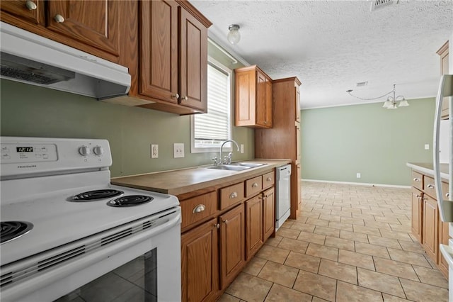 kitchen featuring sink, decorative light fixtures, a textured ceiling, light tile patterned floors, and white appliances