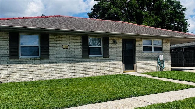 single story home with brick siding, a front lawn, and roof with shingles