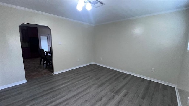 unfurnished room featuring visible vents, arched walkways, dark wood finished floors, and crown molding