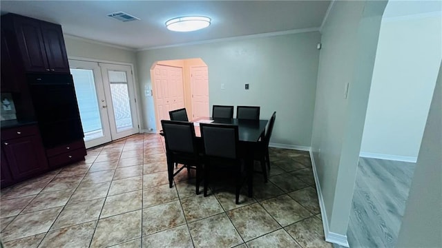 dining area featuring arched walkways, light tile patterned flooring, visible vents, and crown molding