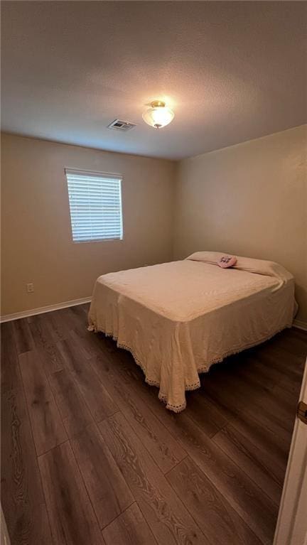 bedroom featuring dark wood-style flooring, visible vents, and baseboards