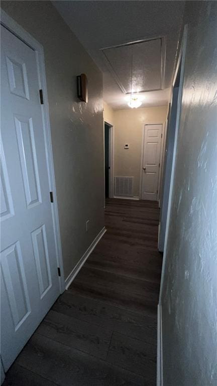 hall with baseboards, attic access, visible vents, and dark wood-style flooring