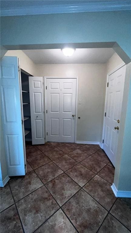 hallway with dark tile patterned floors and baseboards