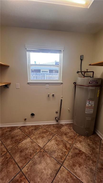 washroom featuring light tile patterned flooring, hookup for a gas dryer, laundry area, baseboards, and water heater