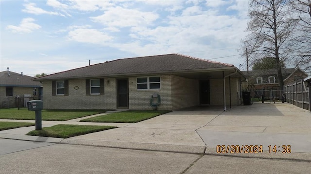 single story home featuring concrete driveway, brick siding, a front lawn, and fence