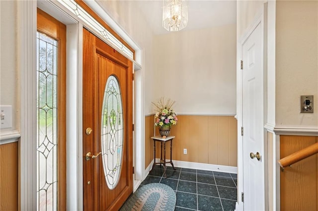 entrance foyer featuring an inviting chandelier and dark tile patterned flooring