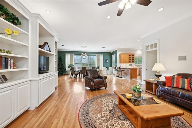 living room featuring ornamental molding, ceiling fan with notable chandelier, light hardwood / wood-style floors, and built in shelves