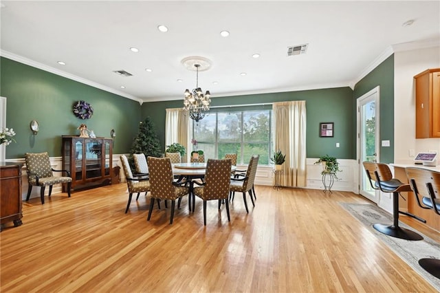 dining space with a notable chandelier, light wood-type flooring, and ornamental molding