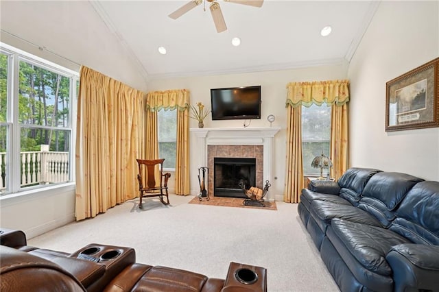 carpeted living room featuring a tile fireplace, ceiling fan, vaulted ceiling, and crown molding