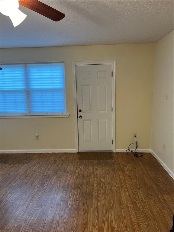 spare room with dark wood-type flooring, a textured ceiling, and ceiling fan