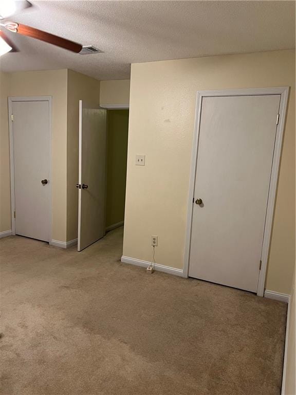 unfurnished bedroom with light carpet, a textured ceiling, and ceiling fan