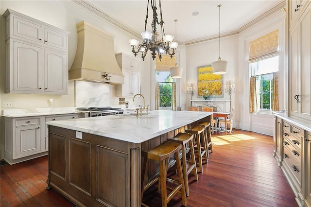 2027 Carondelet St, New Orleans, LA 70130 - kitchen featuring premium range hood, a wealth of natural light, decorative light fixtures, a kitchen bar, and a center island with sink