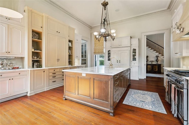 2027 Carondelet St, New Orleans, LA 70130 - kitchen featuring pendant lighting, sink, crown molding, high end stainless steel range, and an island with sink